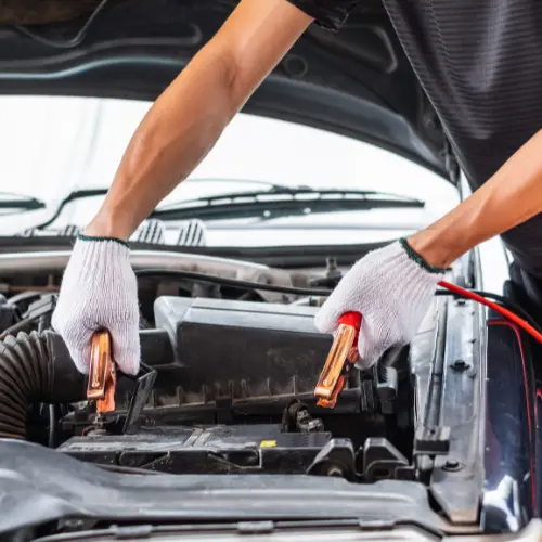 A technician connecting jumper cables to a battery